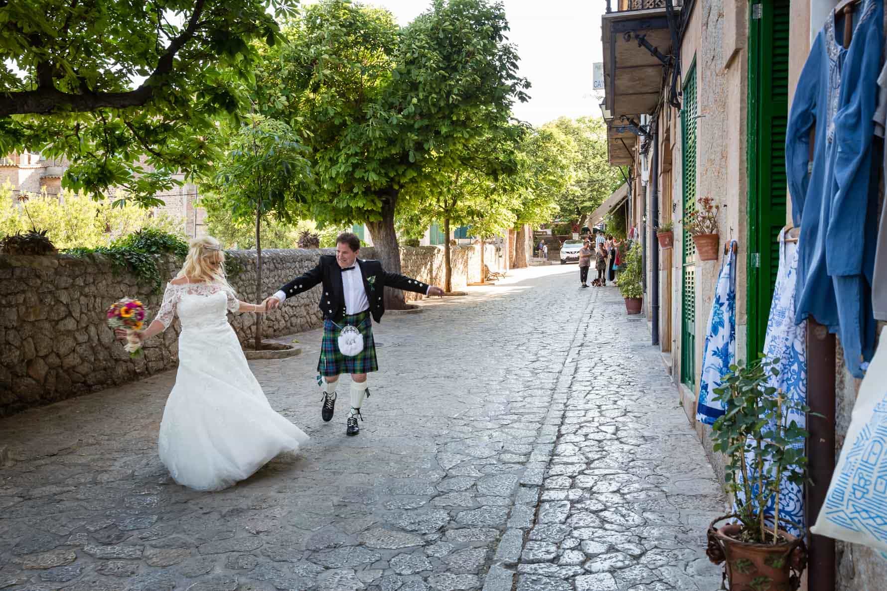 Happy bride and groom dancing in the streets of Valldemossa after their Mallorca wedding