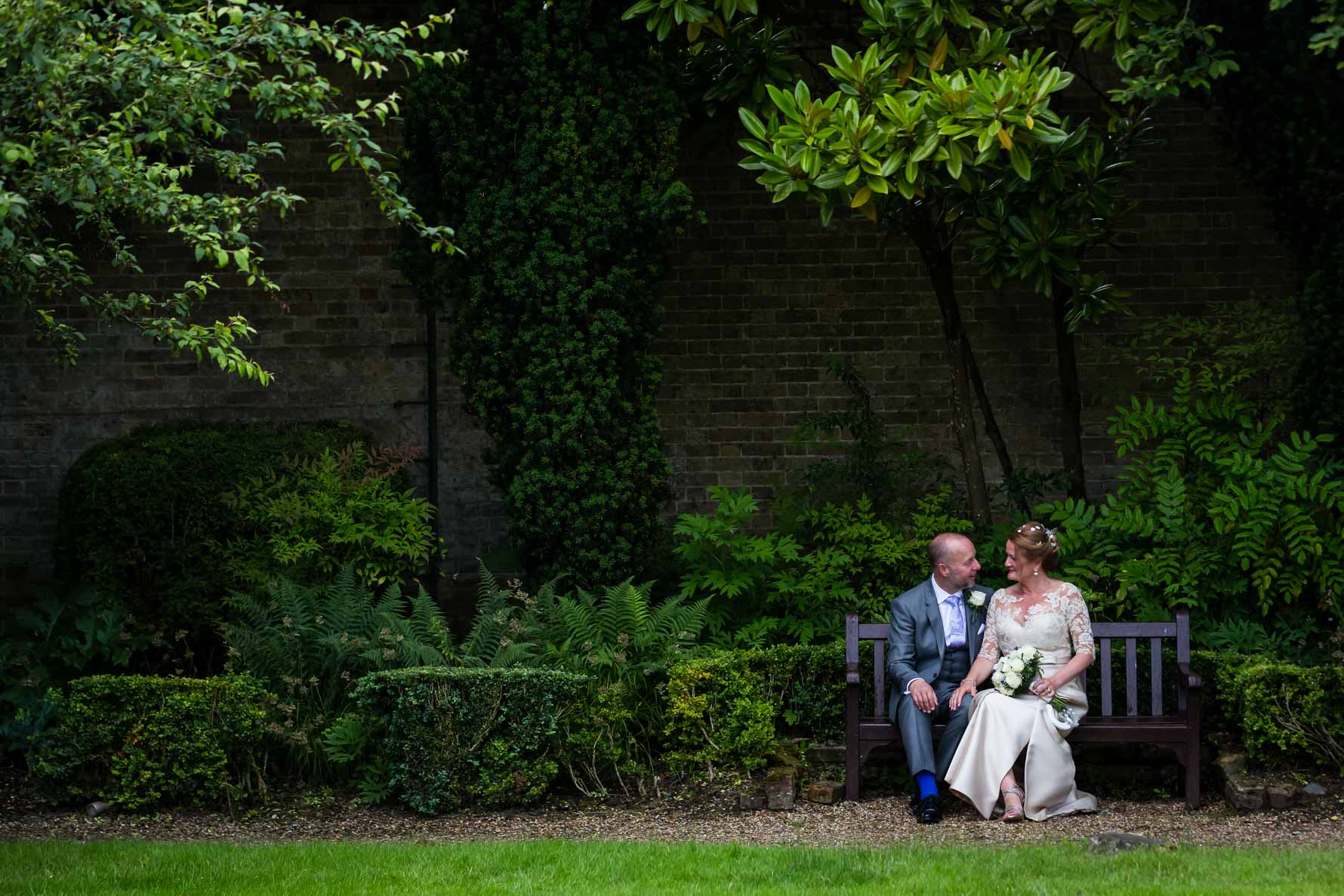 Bride and groom chatting in The Garden Court at Hanbury Manor by Hertfordshire wedding photographer Graham Warrellow