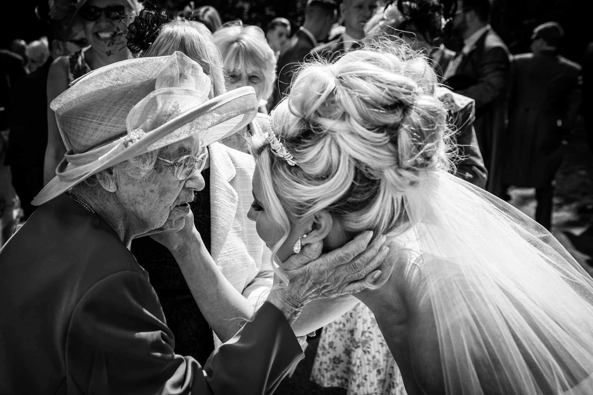 An example of documentary wedding photography as a bride and 104 year old great grandmother touch faces.