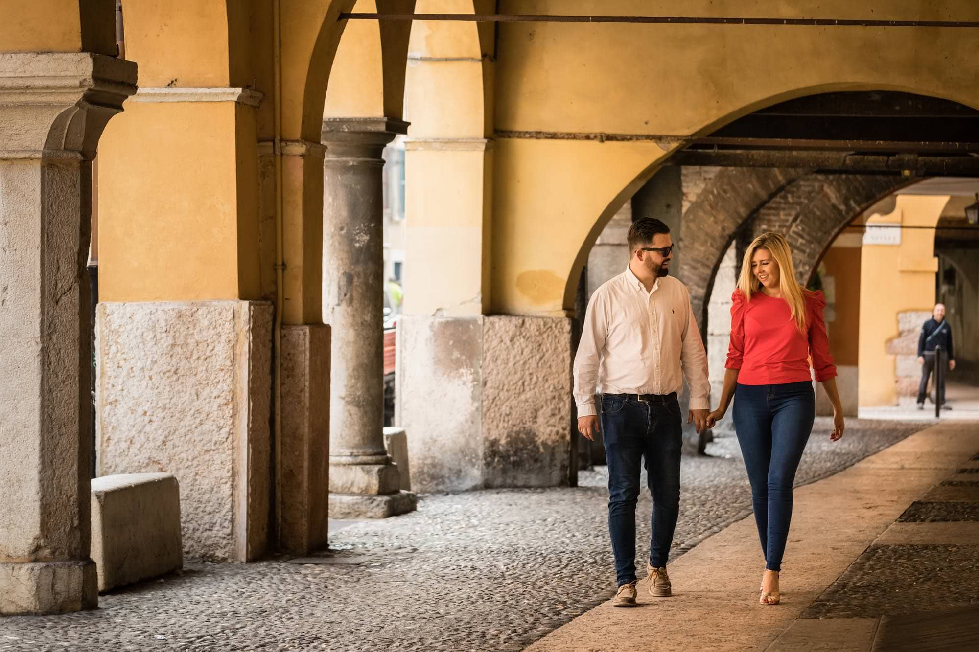 Engaged couple walking under the arches in Verona old town